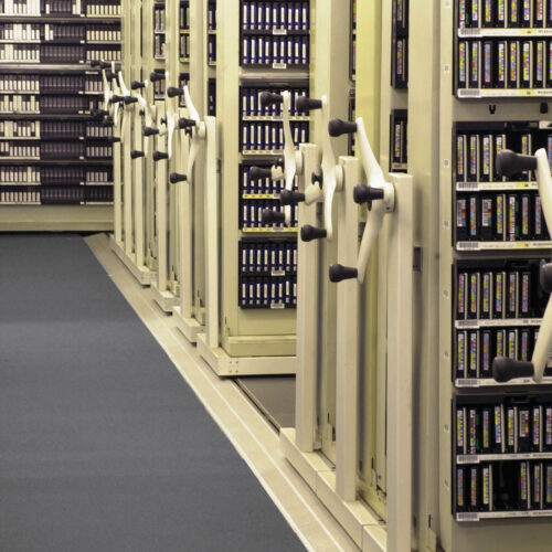 Rows of compact shelving units used for storing media archives and records in a storage facility.