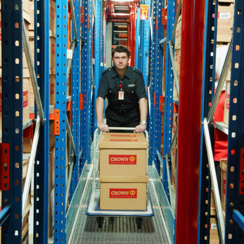 Crown Information Management employee moving archive boxes in a secure storage facility.